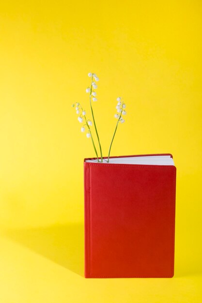 Bloc-notes rouge avec des fleurs de muguet sur fond jaune