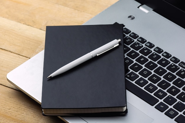 Bloc-notes et stylo sur le clavier de l'ordinateur portable