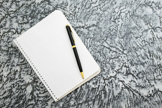 Bloc-notes et stylo sur fond gris texturé