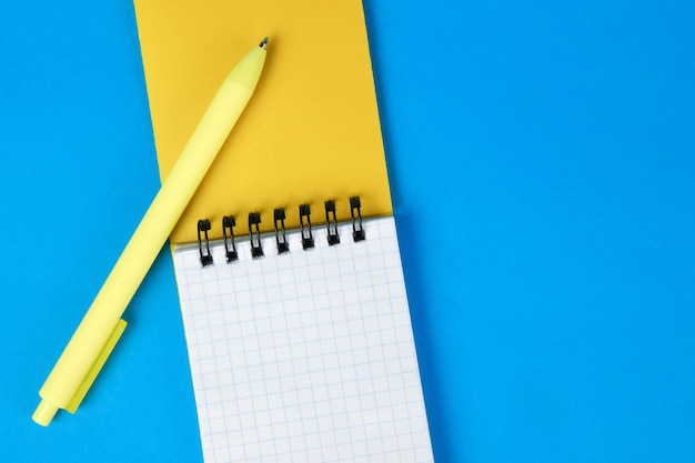 Bloc-notes et stylo jaune sur fond bleu Minimalisme top vie