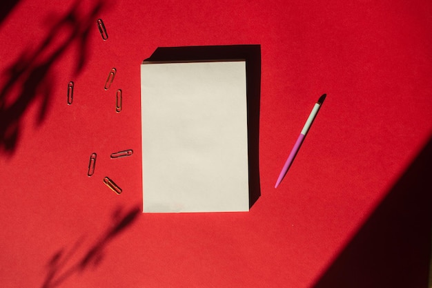 Un bloc-notes avec un stylo se trouve sur un fond rouge coloré Fournitures de bureau