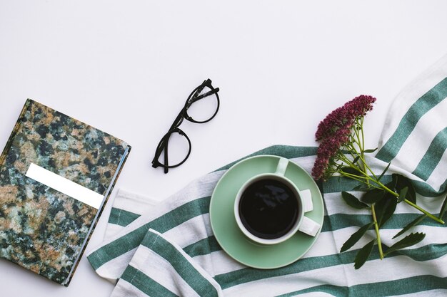 Bloc-notes et tasse de café sur fond blanc.