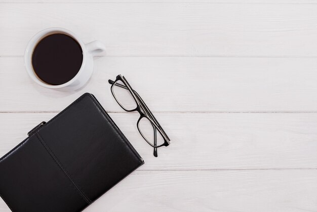 Bloc-notes, verres et une tasse de café sur un blanc