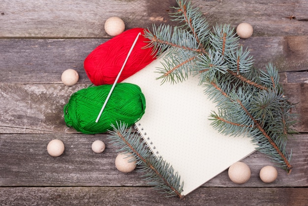 Bloc-notes vide vide avec un motif à pois, fil, crochet, perles en bois et branches de sapin sur une table en bois