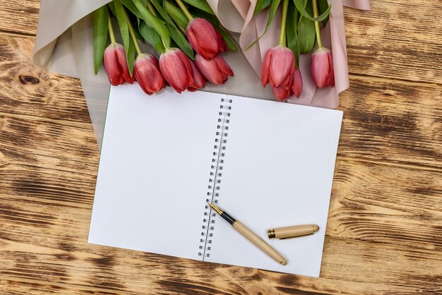 Bloc-notes vierge avec des tulipes sur table en bois