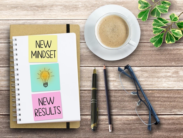 Photo bloc-notes vue de dessus avec texte new mindset new results sur fond de table en bois