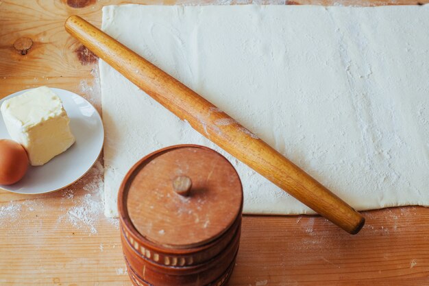 Bloc de pâtisserie fraîchement préparée sur un plan de travail fariné avec un rouleau à pâtisserie en bois