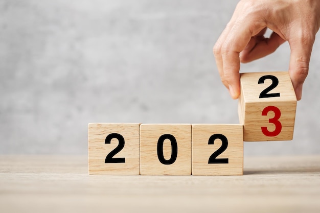 Bloc de retournement à la main 2022 à 2023 texte sur la table Résolution stratégie plan objectif motivation redémarrer les affaires et les concepts de vacances du Nouvel An