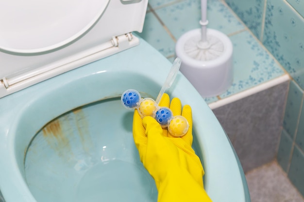 Un bloc sanitaire en plastique jaune bleu qui nettoie les parois des toilettes et rafraîchit la salle de bain