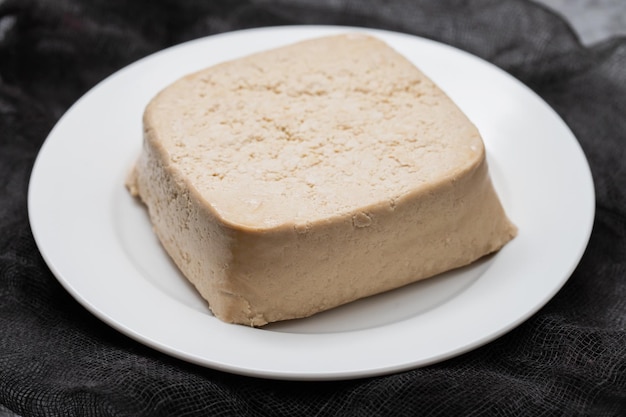 Bloc de tofu cru sur petit plat blanc sur céramique