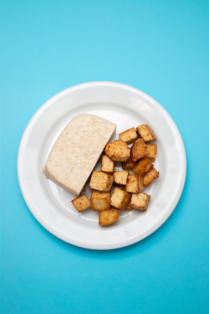 Bloc de tofu cru sur petit plat blanc sur jaune