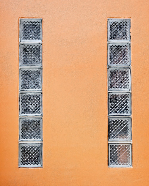 Photo bloc de verre sur le vieux mur de ciment orange