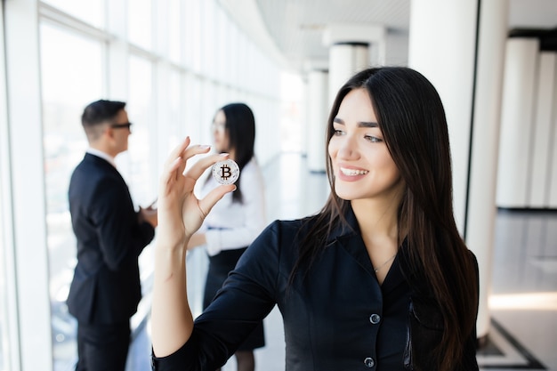 Blockchain et concept d'investissement. Business woman leader holding bitcoin devant son équipe de discussion sur le bureau.