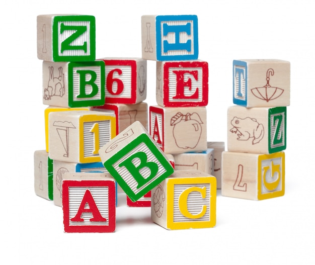 Blocs d'alphabet coloré empilés dans un désordre isolé sur blanc