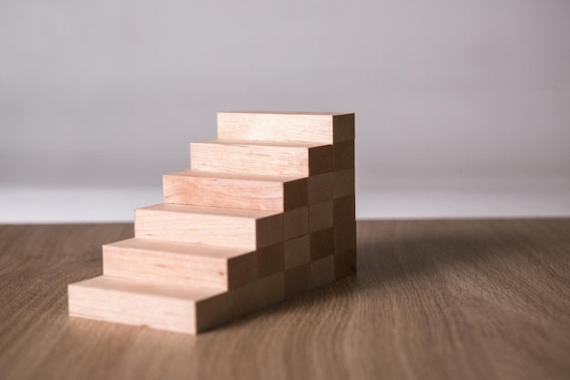 Blocs de bois en forme d'escalier s'appuyant sur le bureau Étape pour réussir en affaires