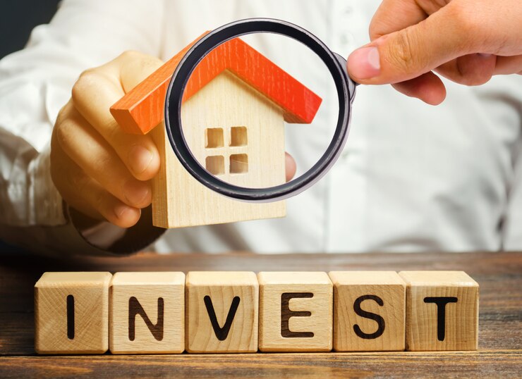 Photo blocs de bois avec le mot invest et maison entre les mains d'un homme d'affaires.