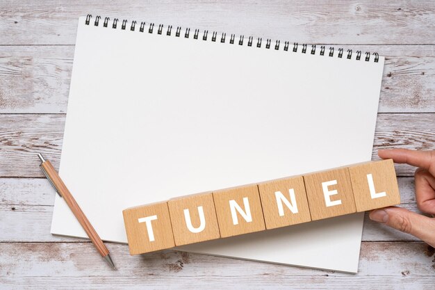 Photo des blocs en bois avec le texte du concept tunnel, un stylo et un carnet.