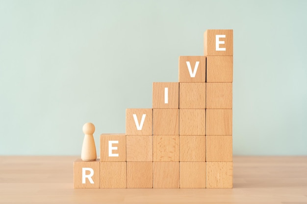 Blocs en bois avec le texte REVIVE du concept et un jouet humain.