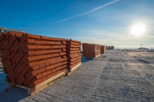 des blocs de briques reposent sur une palette au coucher du soleil