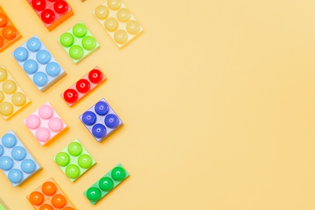 Blocs de jouets. Fond pour les jeux d'enfants. Les constructeurs d'enfants sur jaune. Cubes multicolores. Jeux pour motricité développant la mémoire et l'esprit.