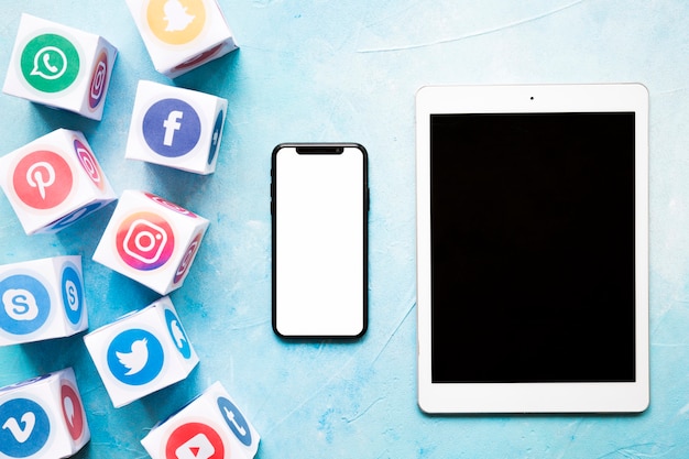 Photo blocs de médias sociaux vives avec téléphone portable et tablette numérique sur mur peint en bleu