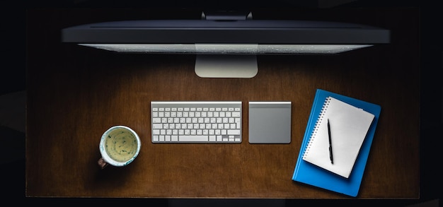 Des blocs-notes d'ordinateur et une tasse de thé sur le bureau la nuit vue de haut