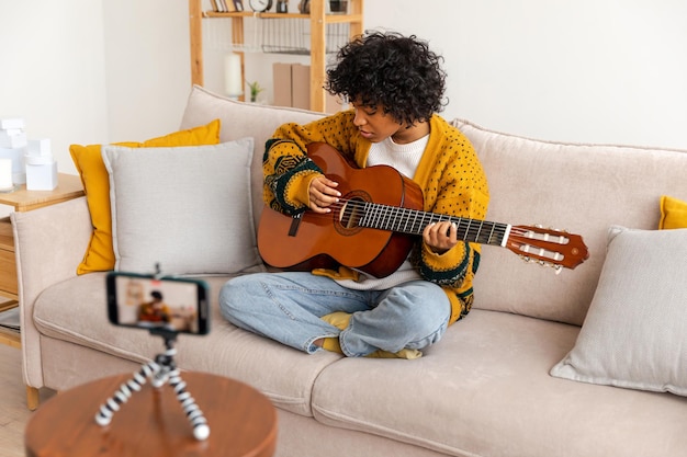 Blogger guitariste heureux fille afro-américaine blogueur jouant de la guitare chantant chanson enregistrement vlog soc