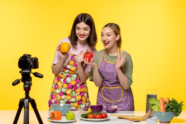 Blogueur culinaire jeune fille en tablier rose enregistrant une vidéo pour les médias sociaux avec un ami heureux