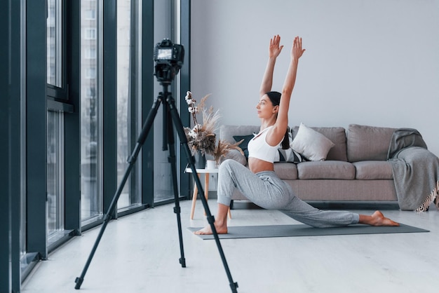 Blogueur jeune femme avec une forme de corps mince en vêtements de sport a une journée de remise en forme à l'intérieur à la maison