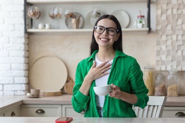 Blogueur vidéo une belle jeune femme à lunettes et une chemise verte est assise devant une caméra Web à