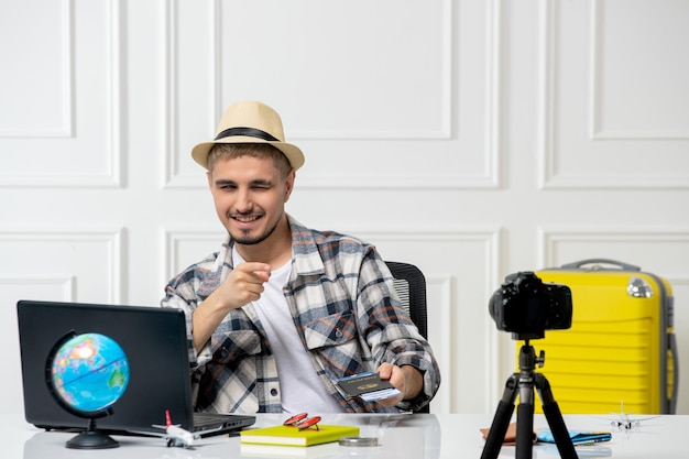 Blogueur de voyage portant un chapeau de paille jeune bel homme enregistrant un vlog de voyage à la caméra très joyeux