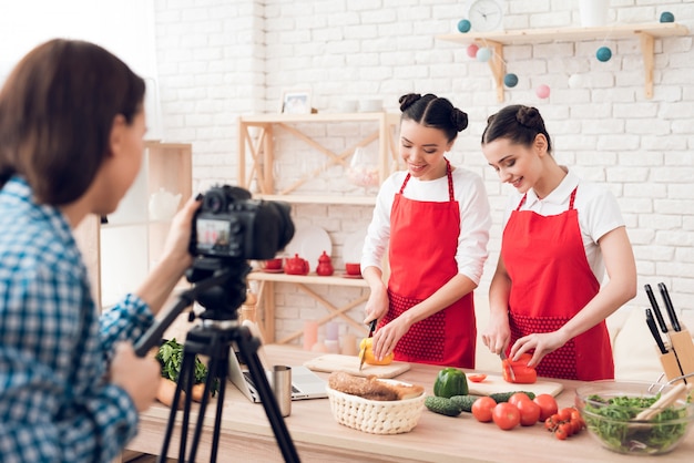 Photo des blogueurs culinaires en tablier rouge coupent en dés les poivrons