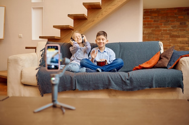 Photo blogueurs d'enfants assis sur un canapé à la caméra, petits vloggers. enfants bloguant en home studio, médias sociaux pour jeune public, diffusion internet en ligne