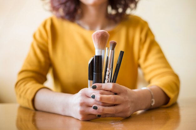 Photo une blogueuse brune montrant des pinceaux à maquillage