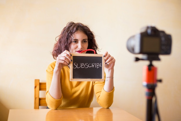 Photo une blogueuse brune montrant un tableau à la caméra