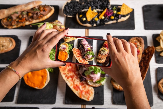 Une blogueuse culinaire prend des photos des plats sur la table du restaurant. Vue de dessus. Déjeuner d'amis, milieux de médias sociaux