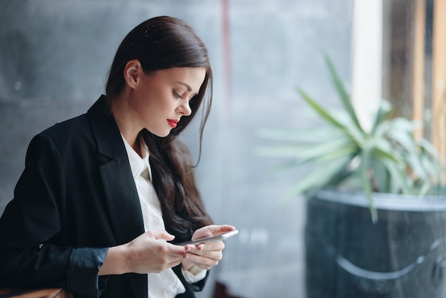 Une blogueuse élégante est assise dans un café avec un téléphone dans les mains lit un message communication mobile et Internet à l'étranger appel vidéo travail indépendant en ligne