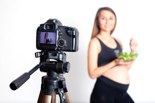 Une blogueuse enceinte enregistre une vidéo à la caméra sur une bonne nutrition pendant la grossesse