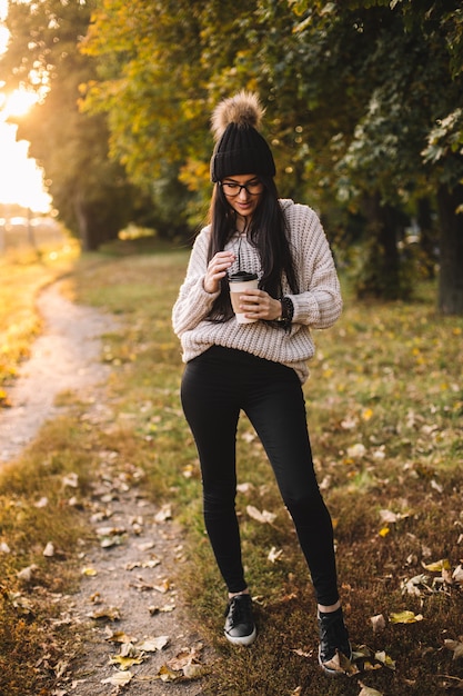 Blogueuse jeune femme avec une tasse de café dans le parc