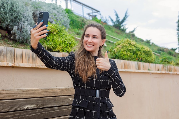 Une blogueuse souriante prend un selfie par un geste parfait dans le parc