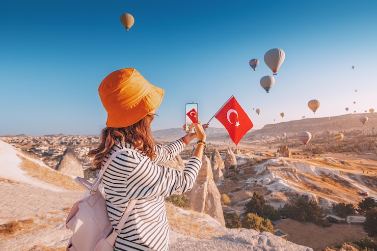 Photo une blogueuse voyageuse prend des photos de ballons volants en cappadoce et du drapeau turc influenceur des médias sociaux