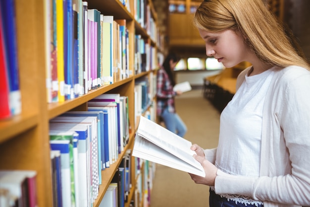 Blond étudiant livre de lecture dans la bibliothèque