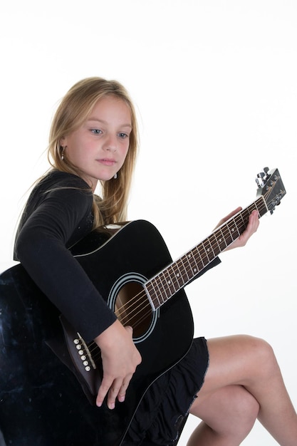 Blond kid girl learning jouer de la guitare isolé