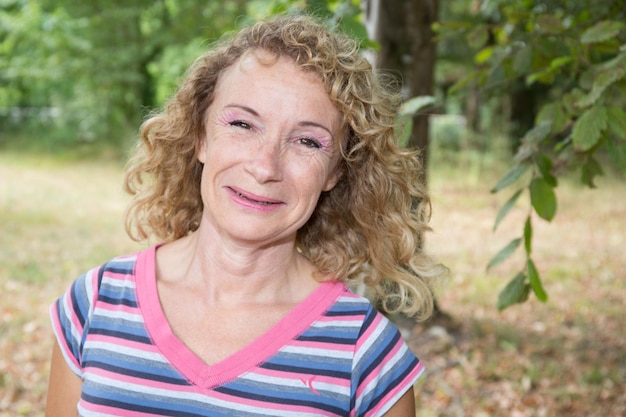 Blond smiling senior woman outdoor heureux d'être là