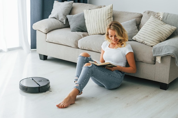 Blonde assise sur le sol Femme en vêtements décontractés est à l'intérieur à la maison