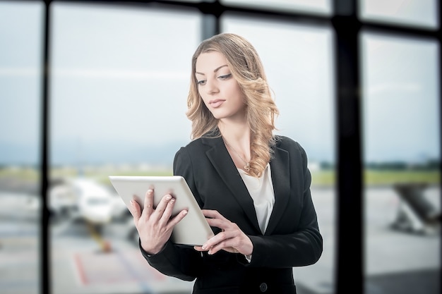 Blonde belle femme d'affaires travaillant sur ordinateur portable en attendant son vol dans un aéroport