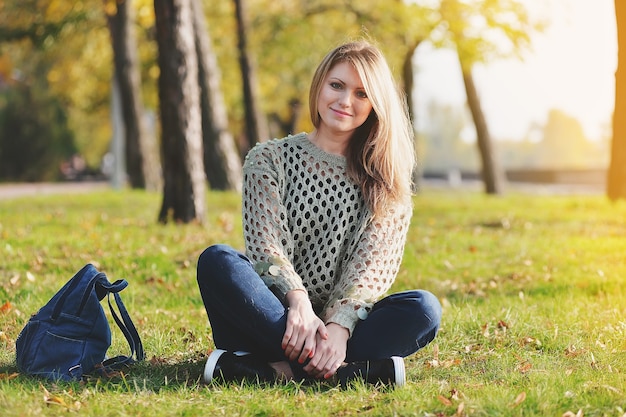 Blonde est assise sur l'herbe verte dans le parc