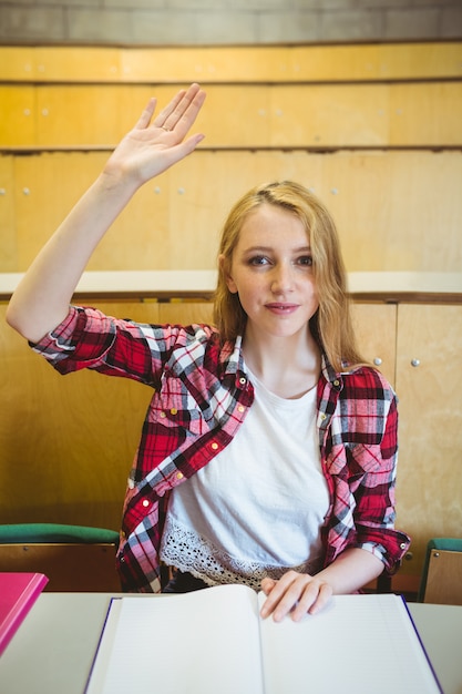 Photo blonde étudiante levant la main pendant le cours