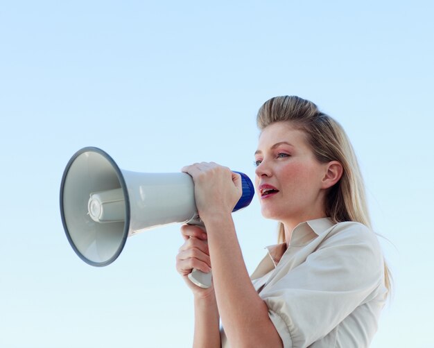 Blonde femme d&#39;affaires criant à travers un mégaphone