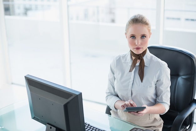 Blonde femme d&#39;affaires sérieuse à l&#39;aide de la calculatrice